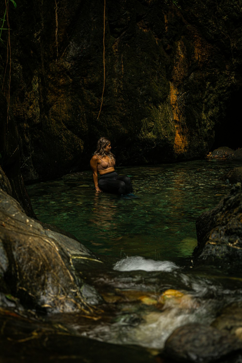 Un homme assis sur un rocher dans une rivière
