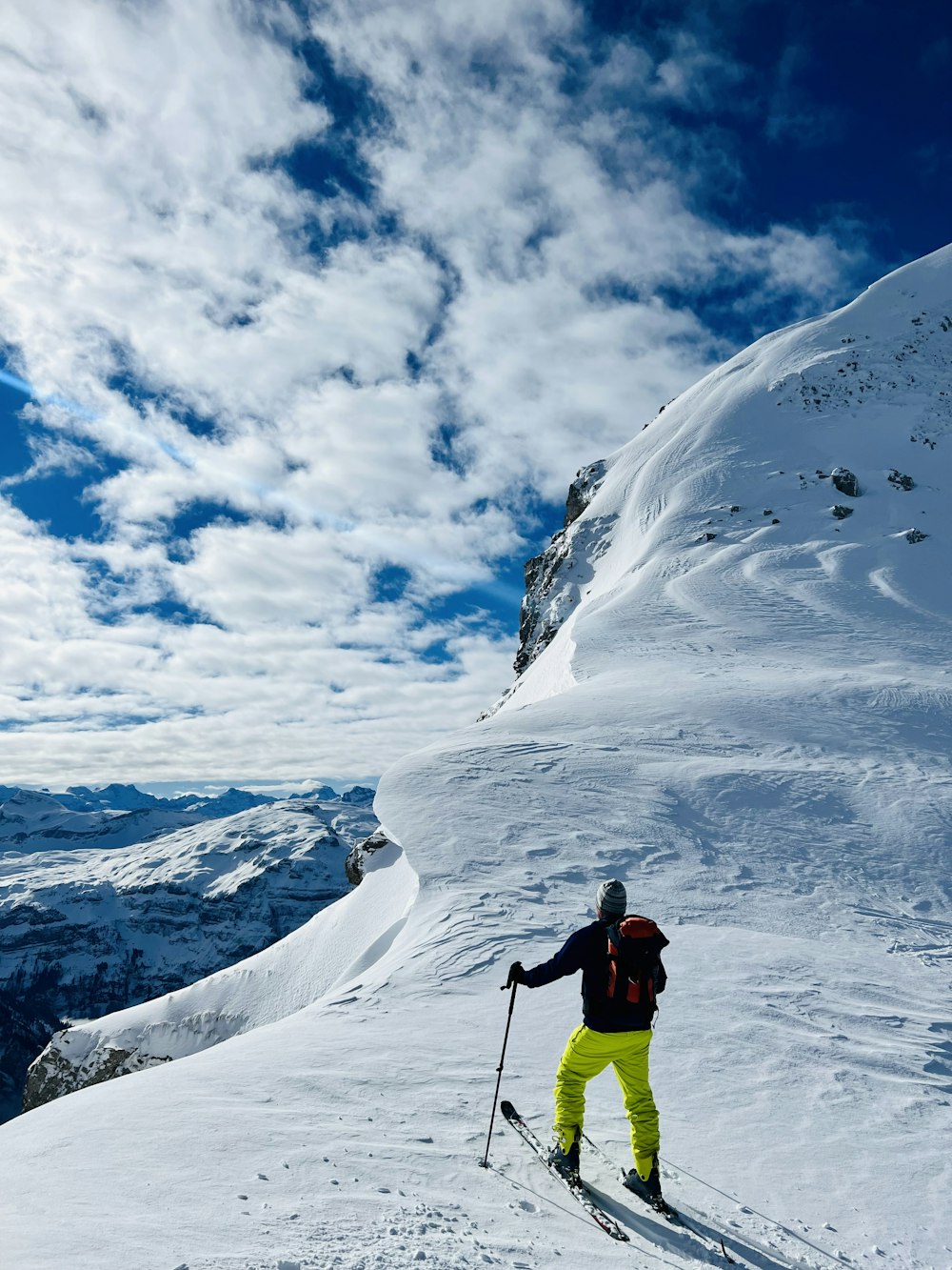 Un homme à skis sur le flanc d’une pente enneigée