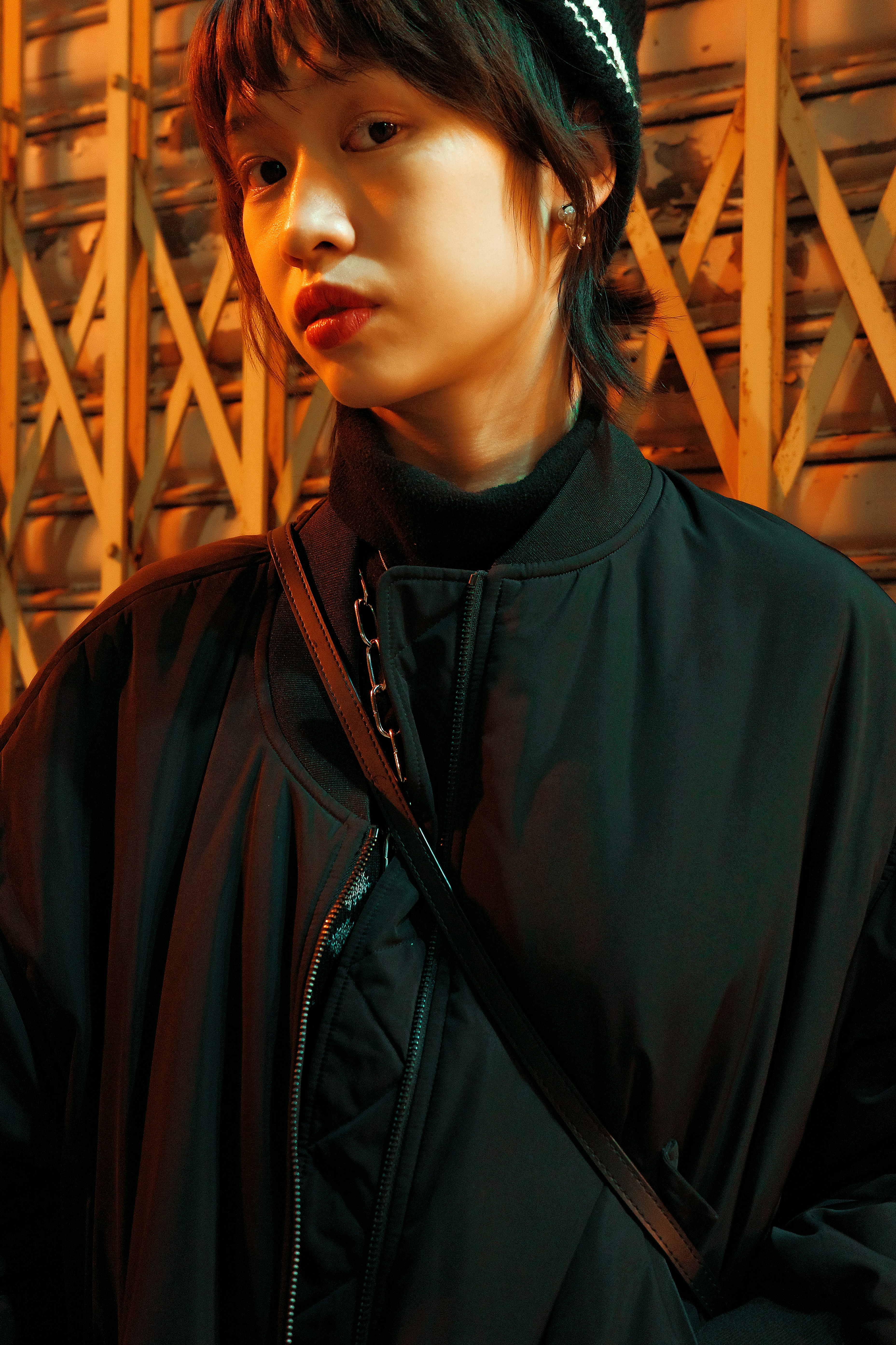 a young man wearing a black jacket and a hat