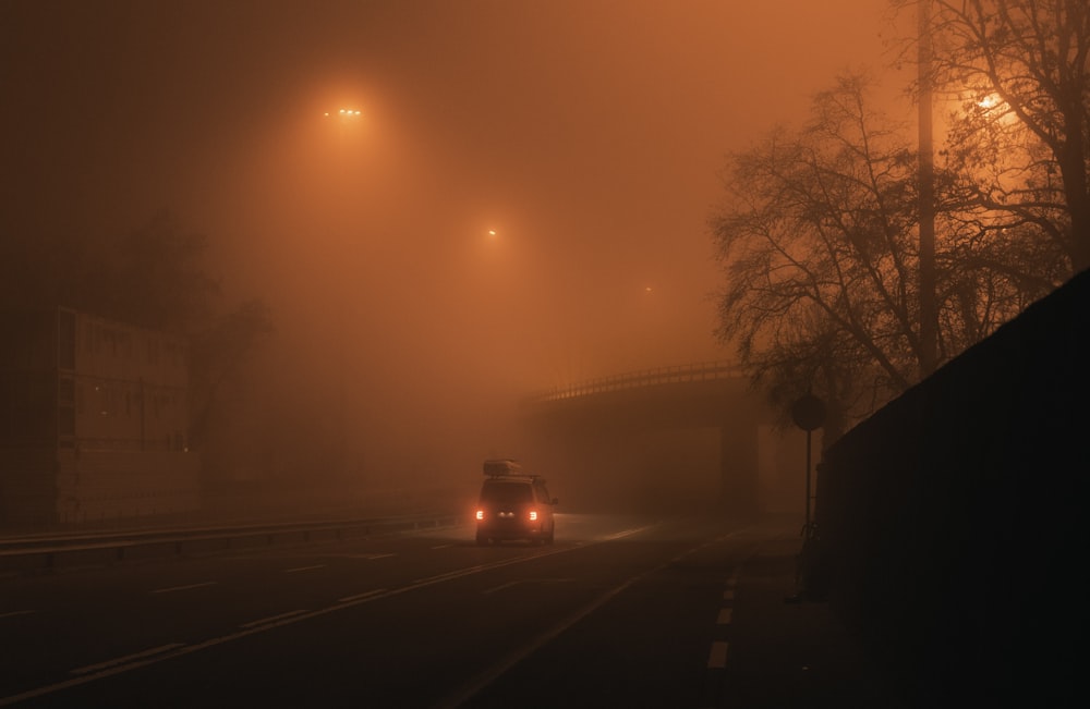 a car driving down a foggy street at night