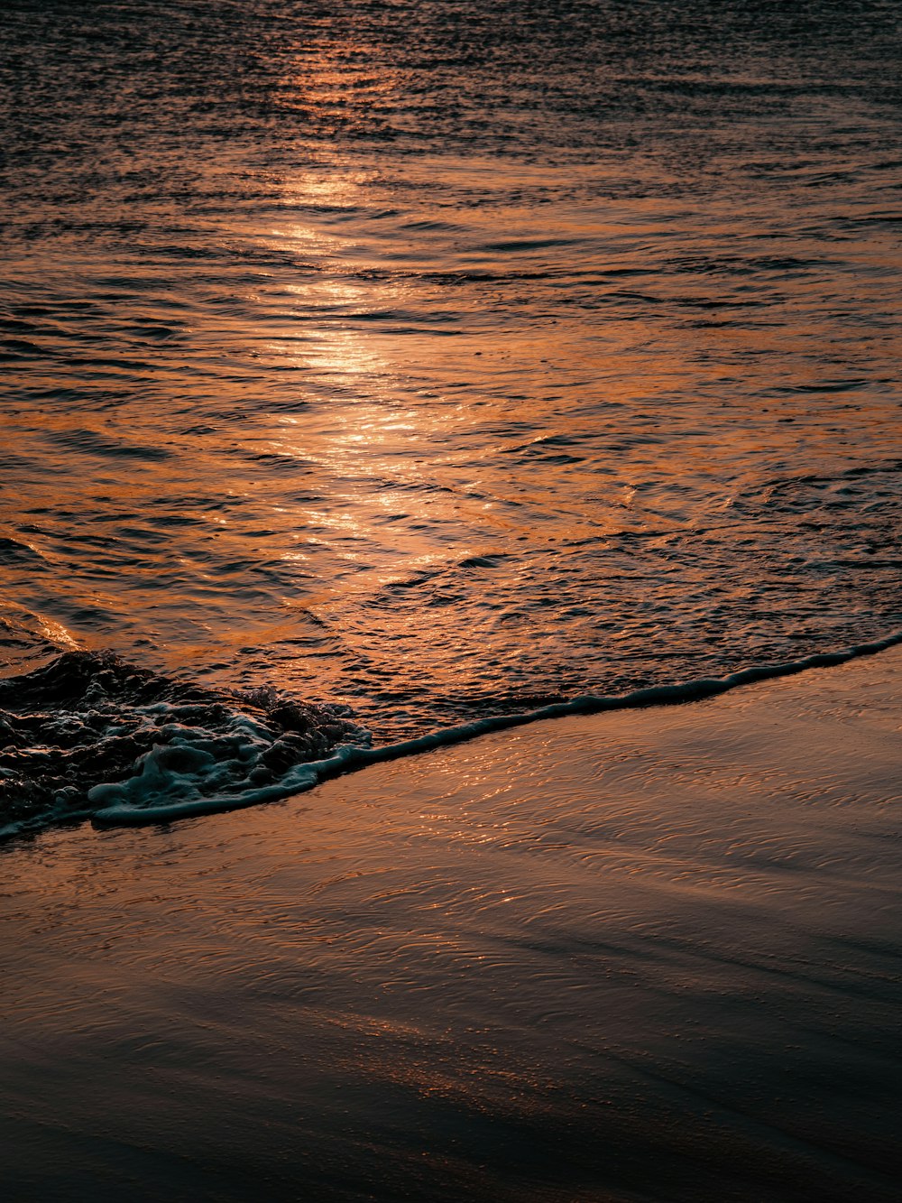 the sun is setting over the water at the beach