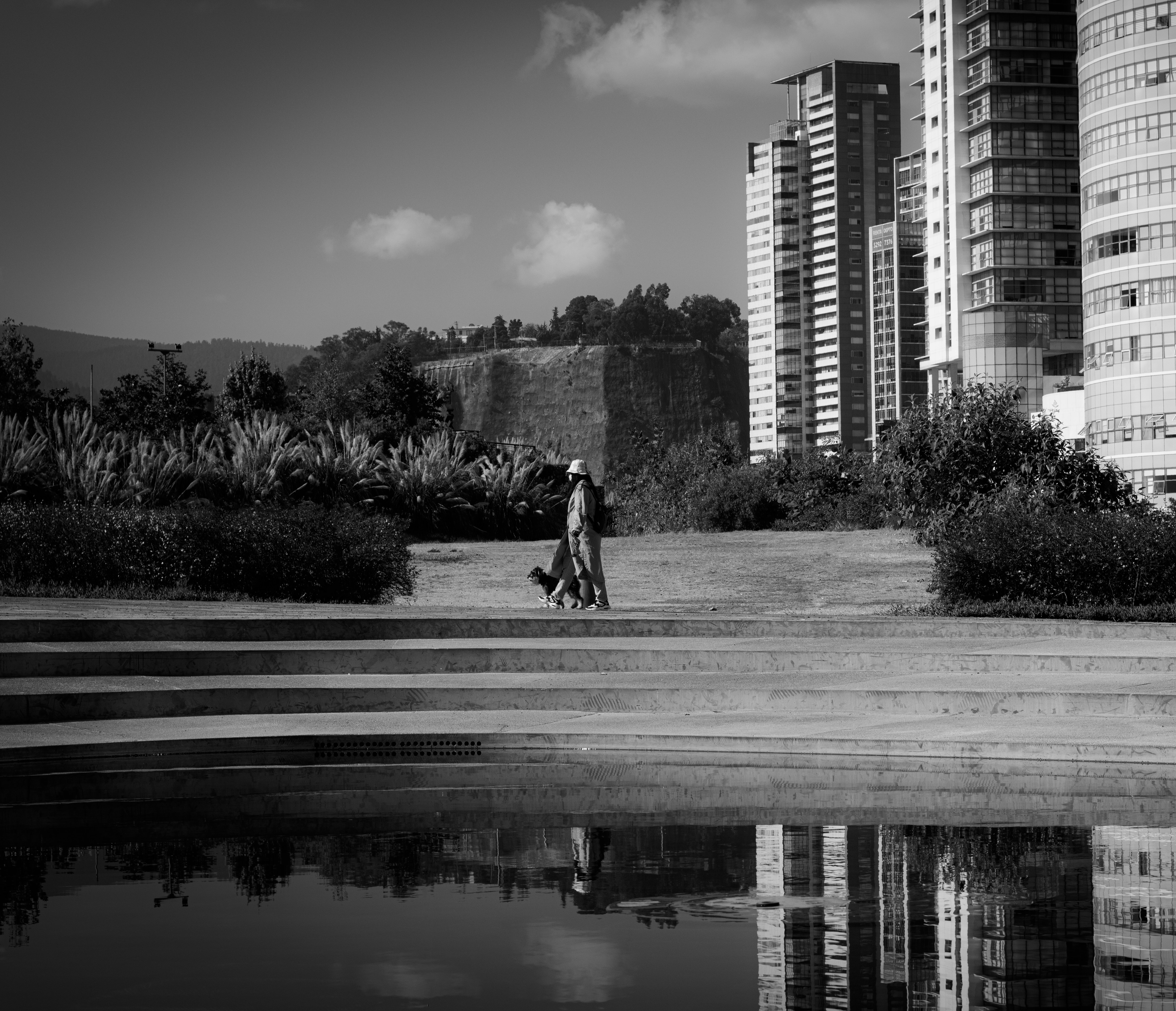 a couple of people walking down a street next to tall buildings