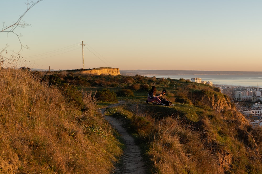 a couple of people sitting on top of a hill