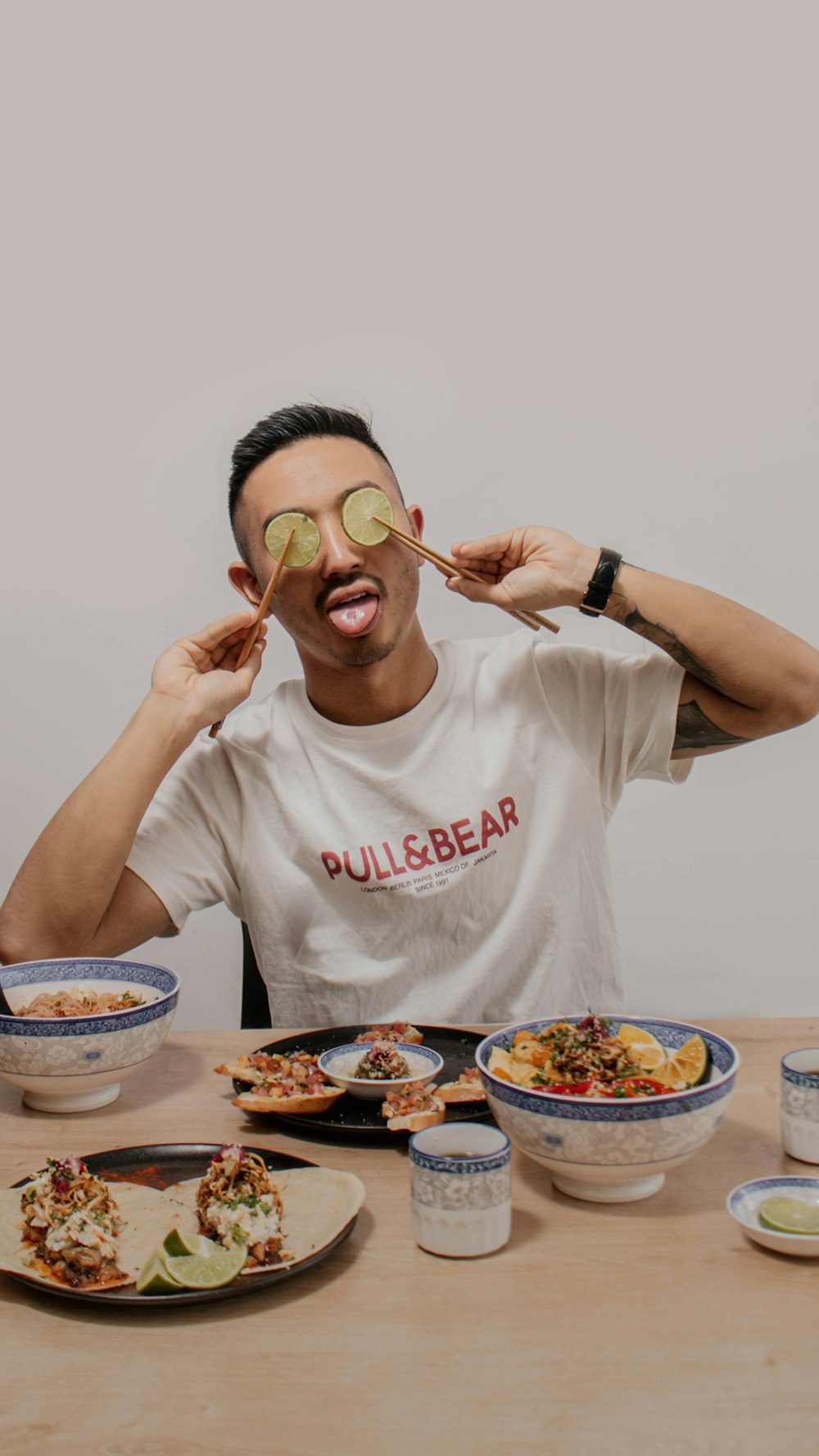 a man with a cucumber on his face sitting at a table