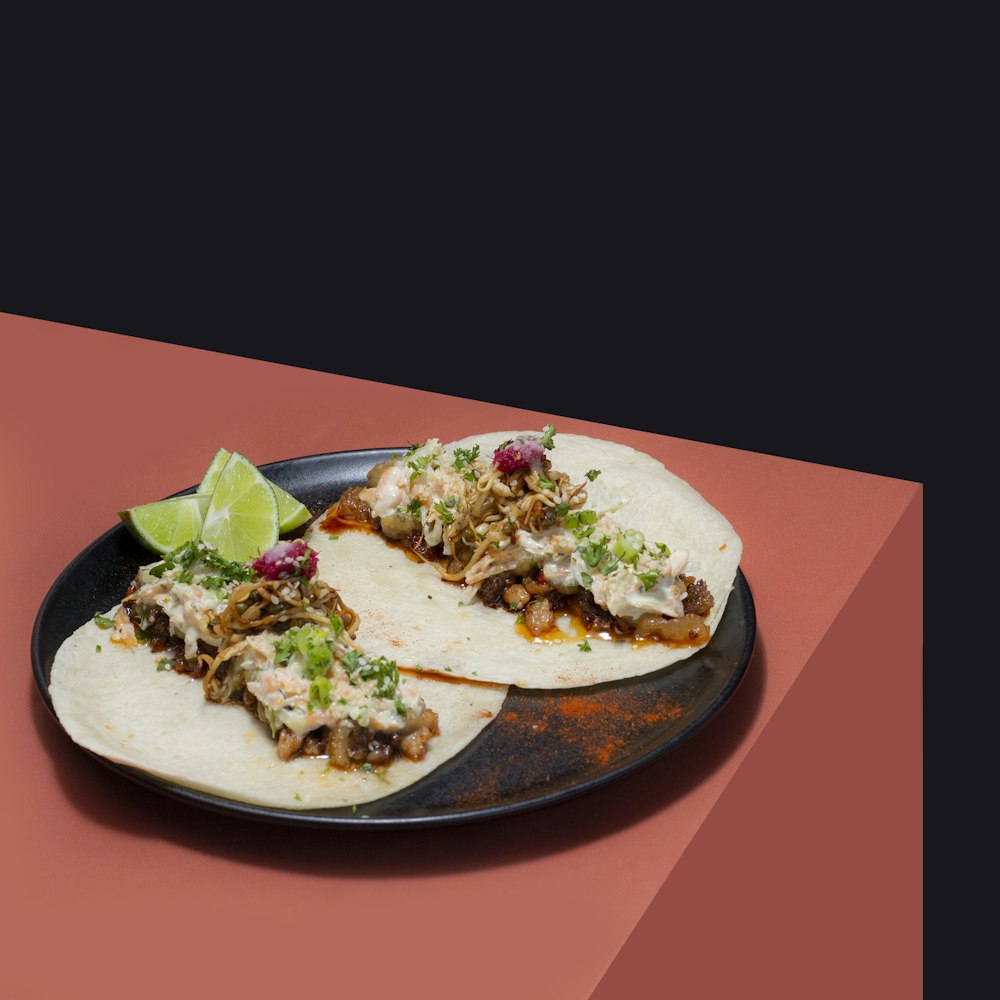 two tacos on a plate with a lime wedge