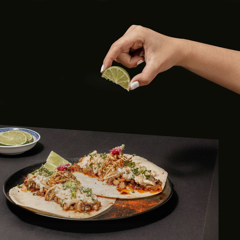 a person holding a piece of food over a plate of food