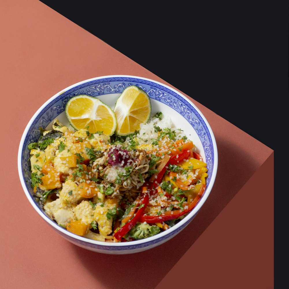 a blue and white bowl filled with food on top of a pink table