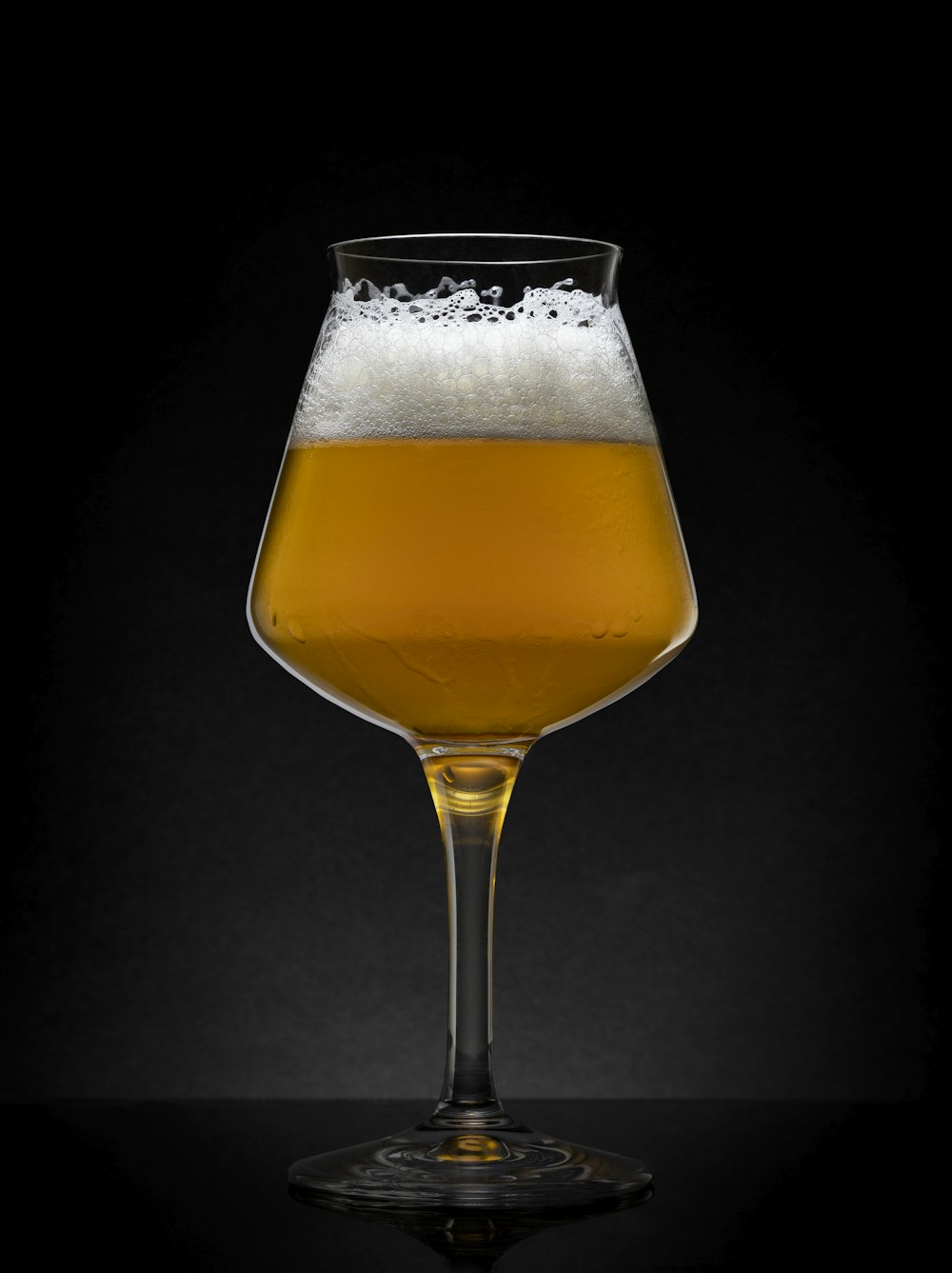 a glass of beer on a black table