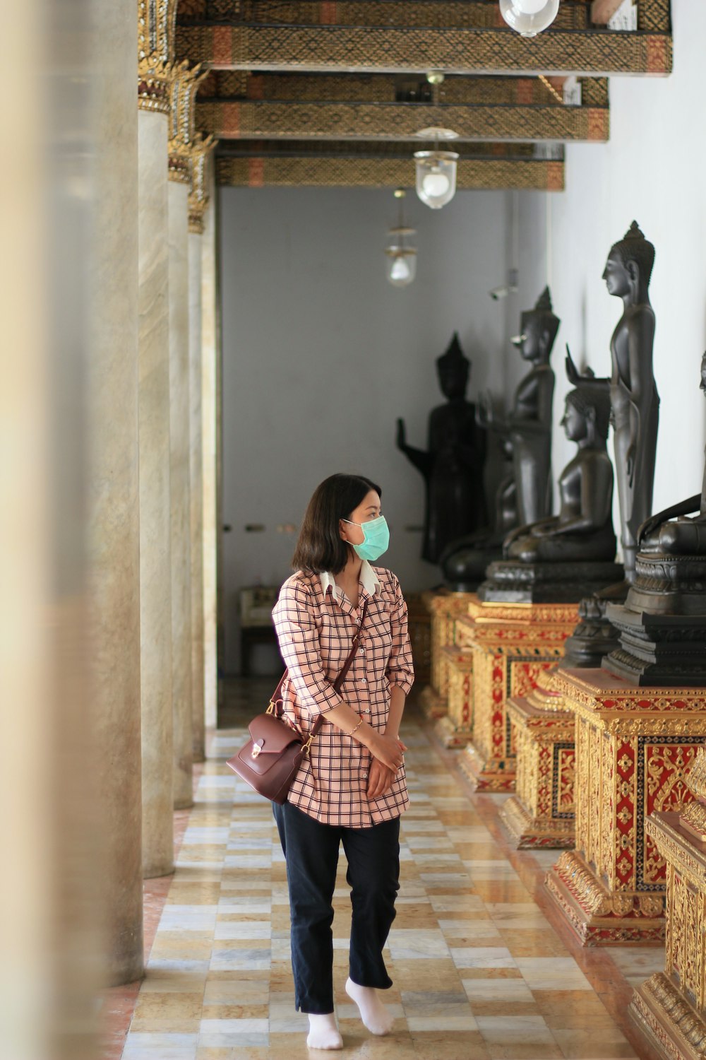 a woman wearing a face mask while walking down a hall