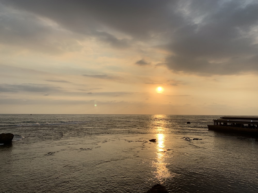 the sun is setting over the water at the beach