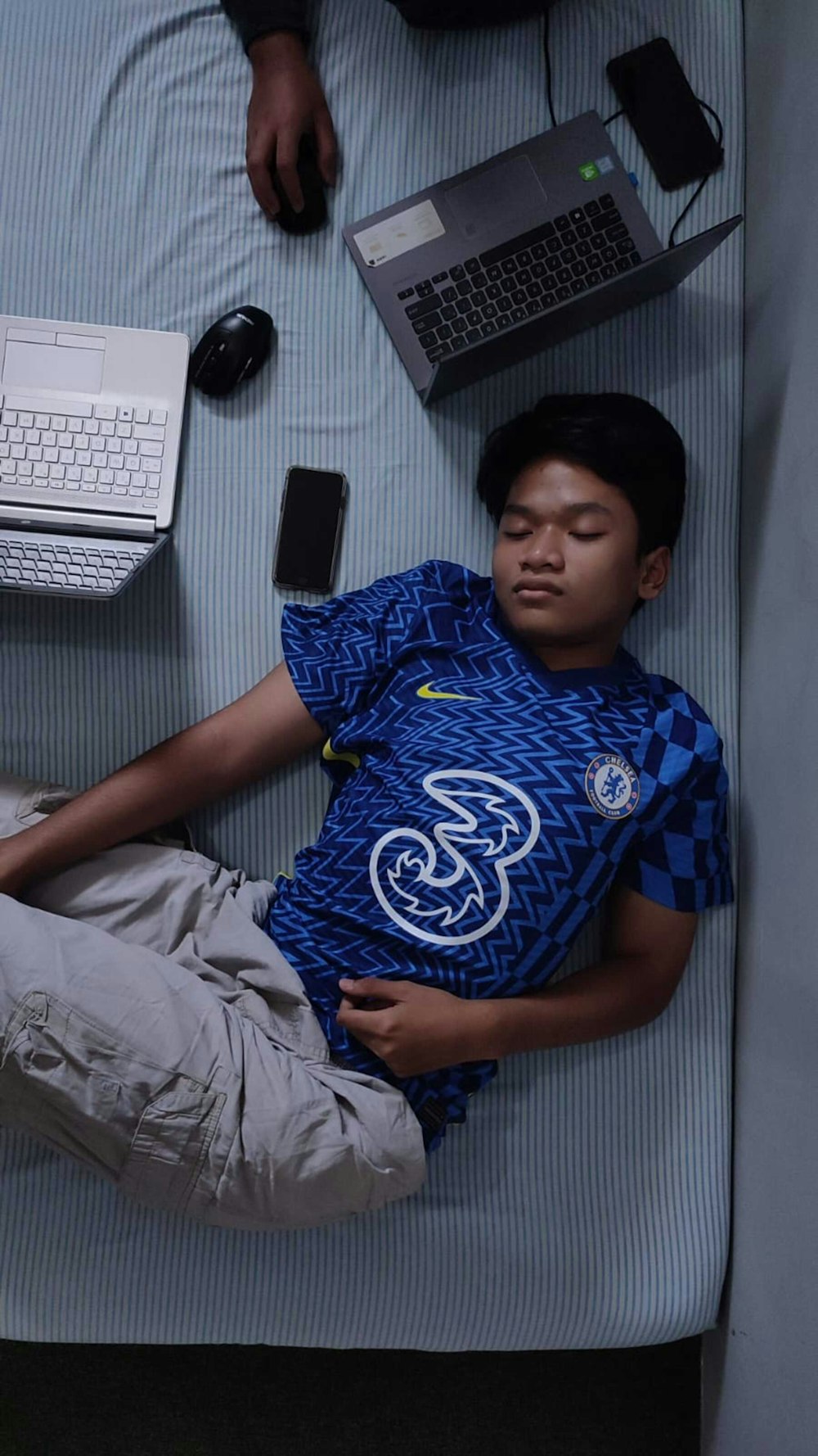 a man laying on a bed with a laptop and a keyboard