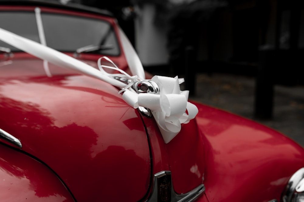 a red car with a white ribbon tied to it