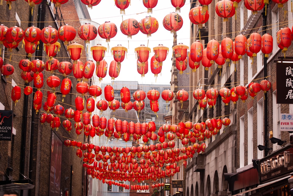 a city street with lots of red lanterns hanging from the ceiling