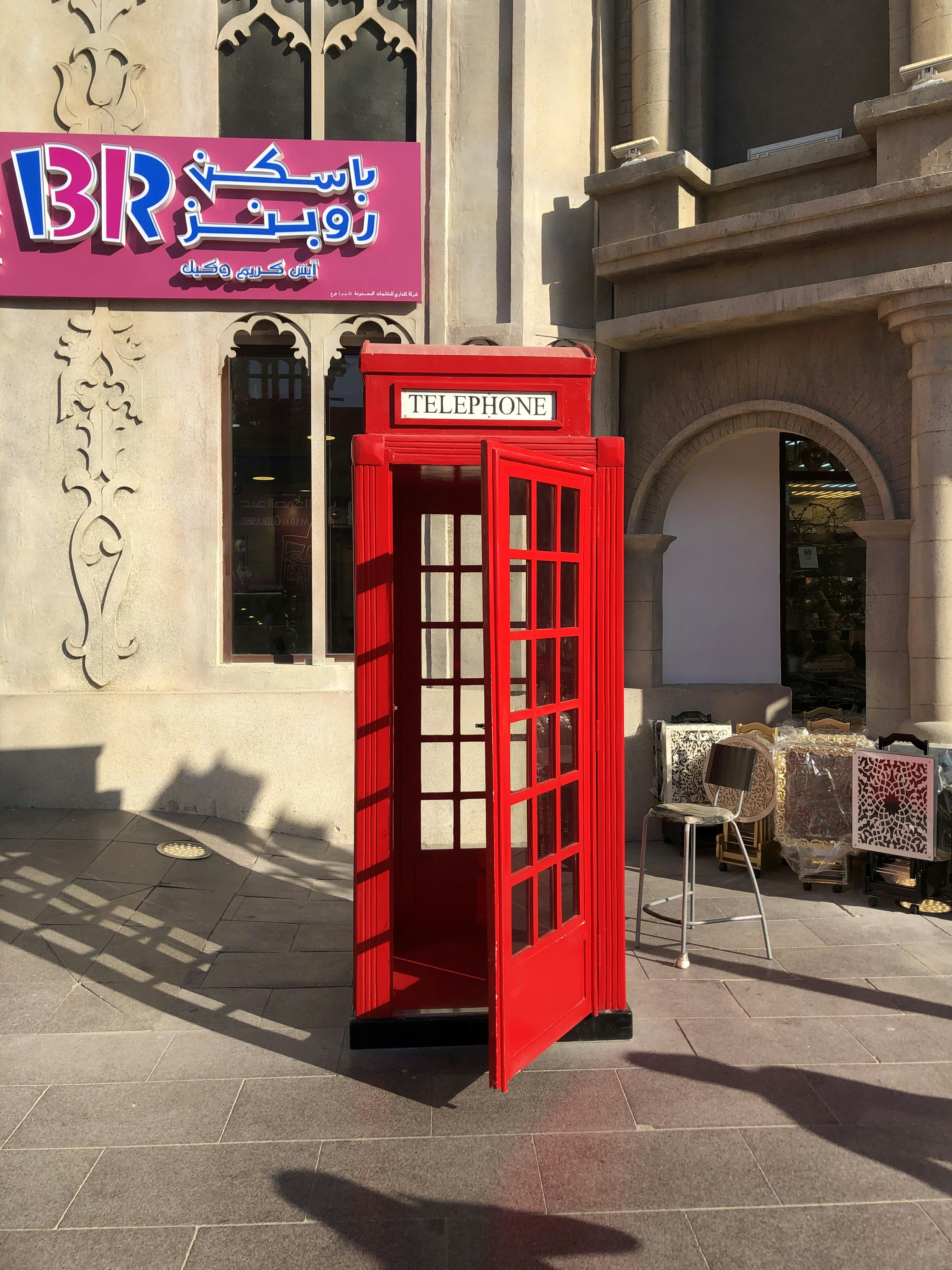 A red phone booth in front of a building photo – Free Dubai Image on ...