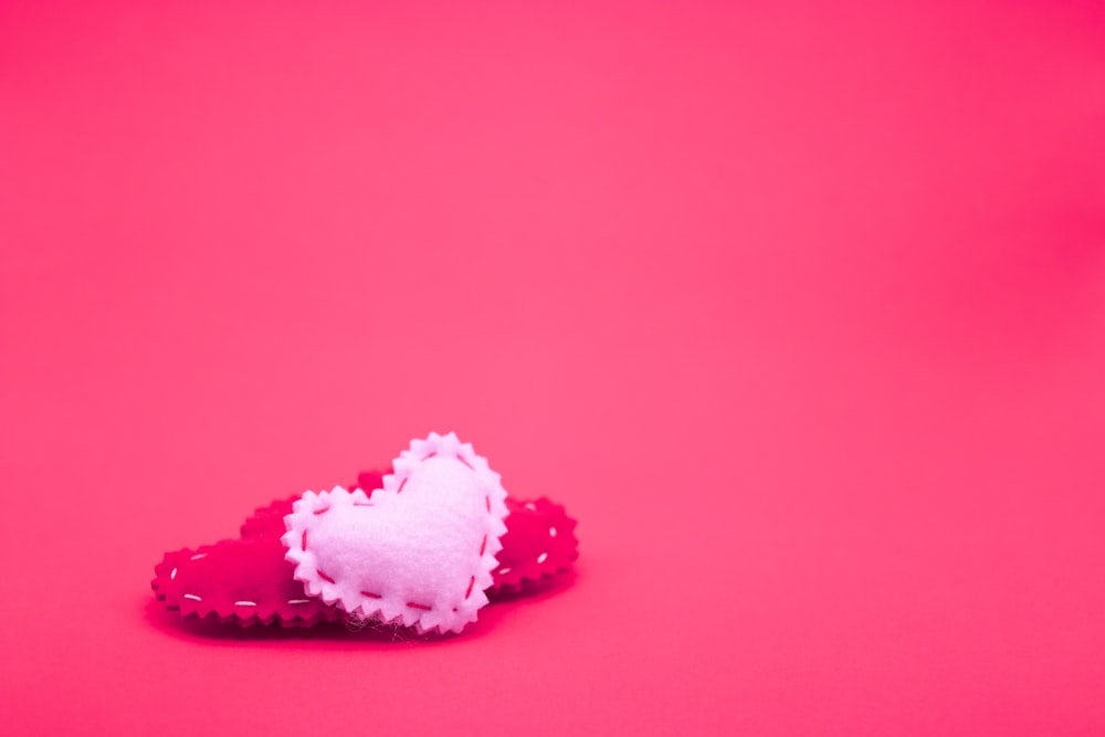 two heart shaped candies on a pink background