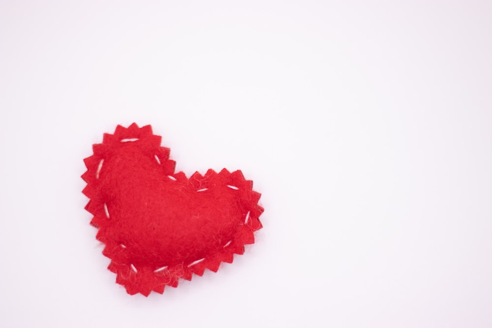 a red felt heart on a white background