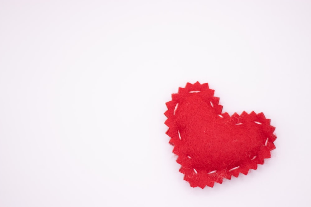 a red felt heart on a white background