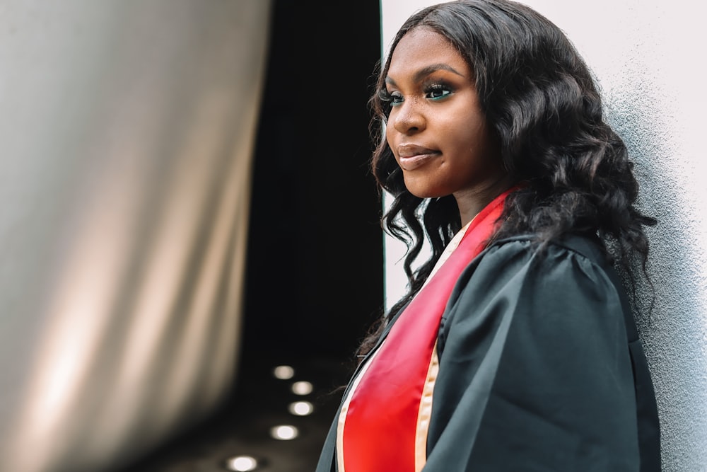 a woman in a graduation gown leaning against a wall