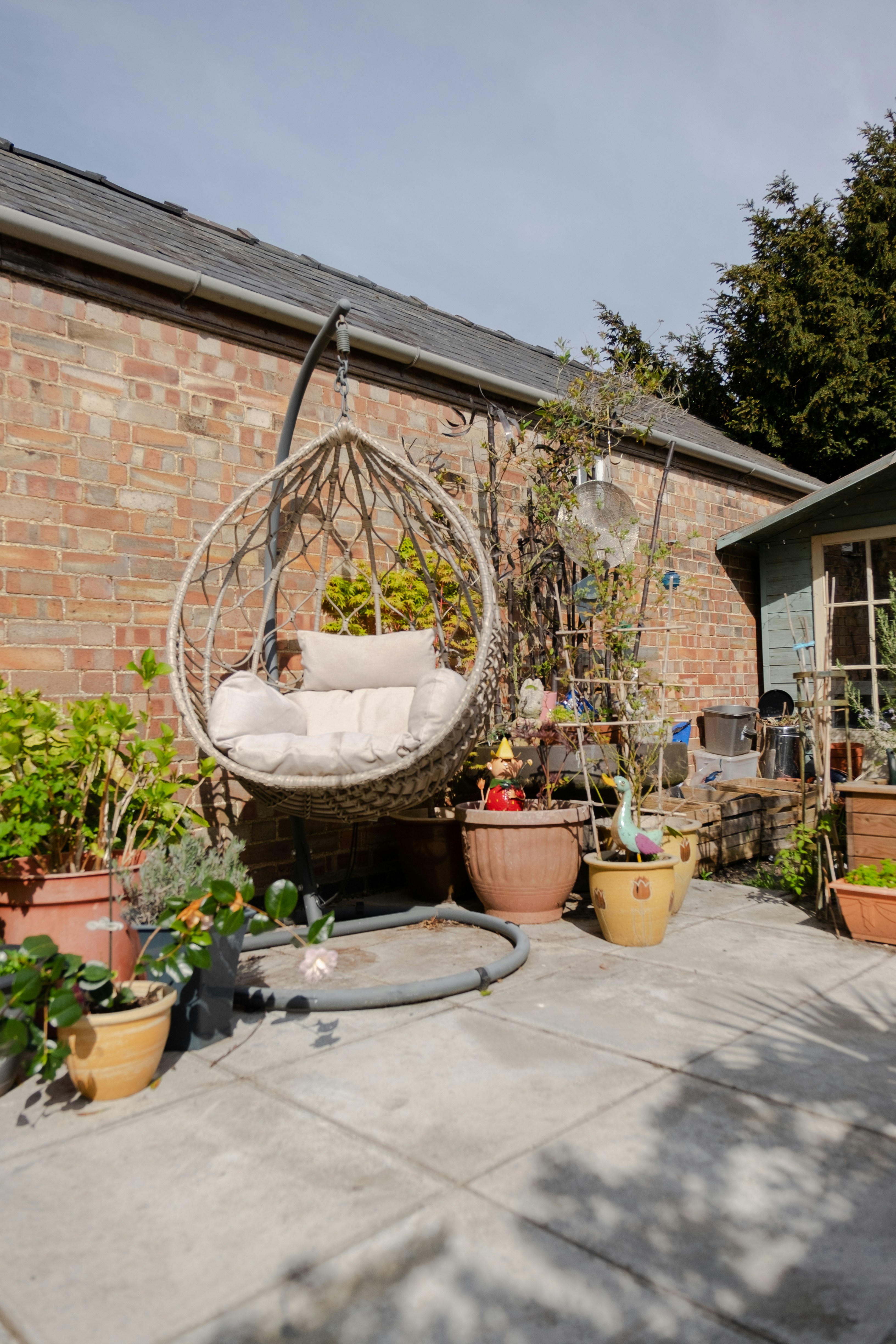 a patio with potted plants and a hanging chair