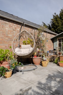 a patio with potted plants and a hanging chair