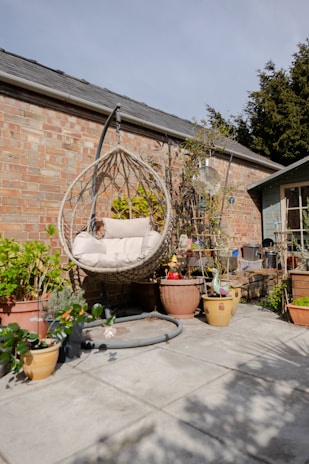 a patio with potted plants and a hanging chair