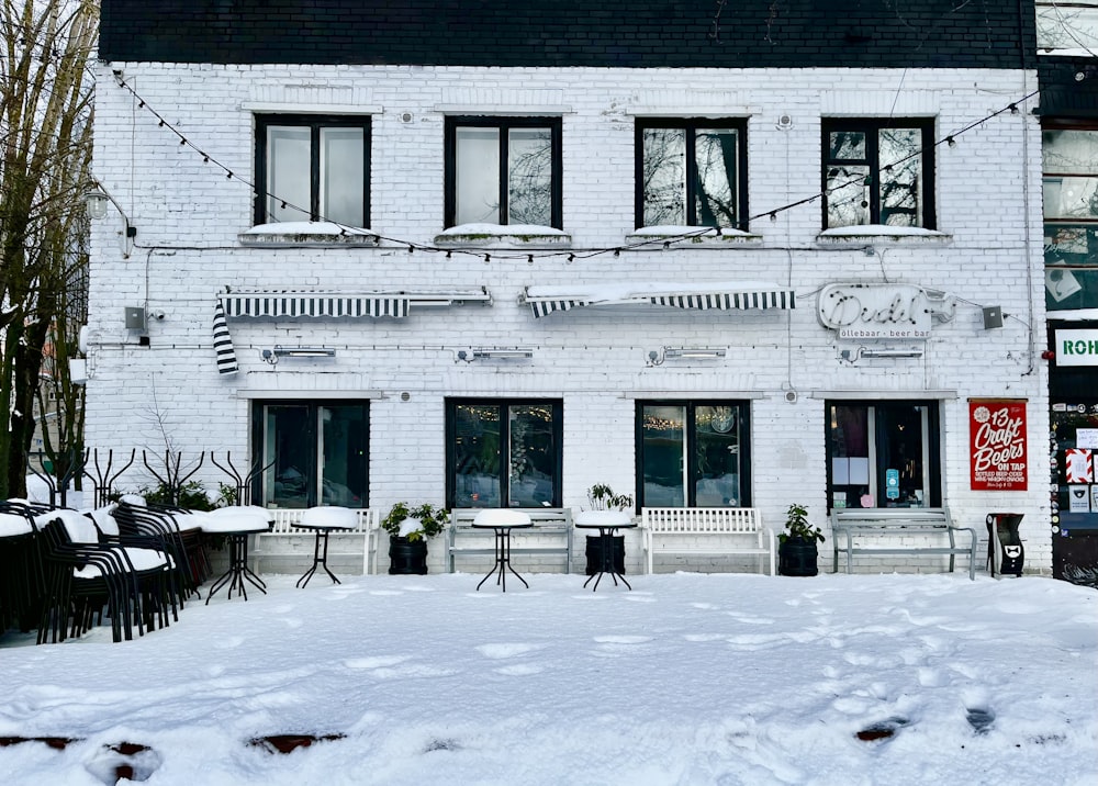 a white building with tables and chairs covered in snow