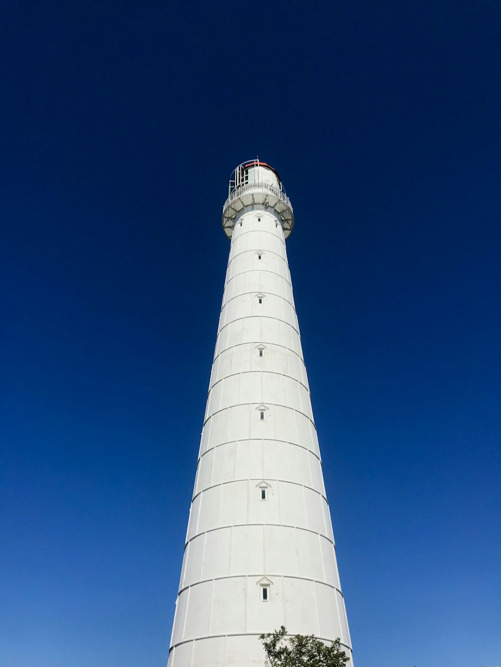 a tall white lighthouse sitting on top of a lush green field