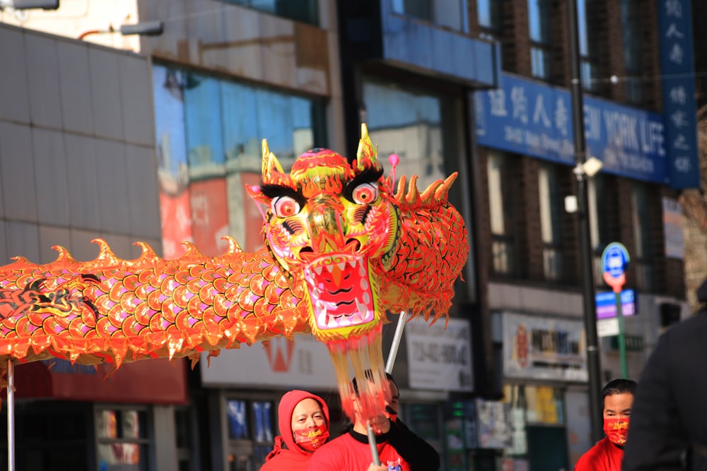 a woman in a red headdress holding a dragon lantern