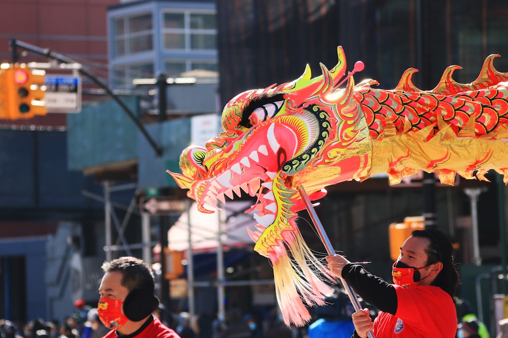 a woman in a red shirt is holding a dragon kite