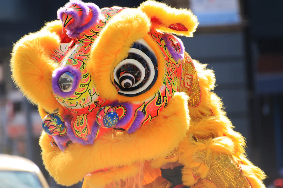 A yellow and orange lion dance head in the street