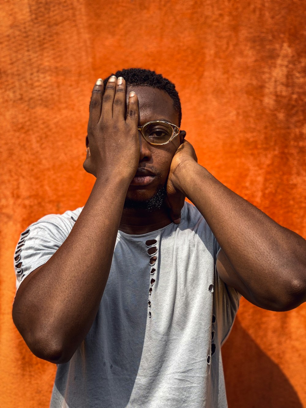 a man with glasses covering his eyes with his hands