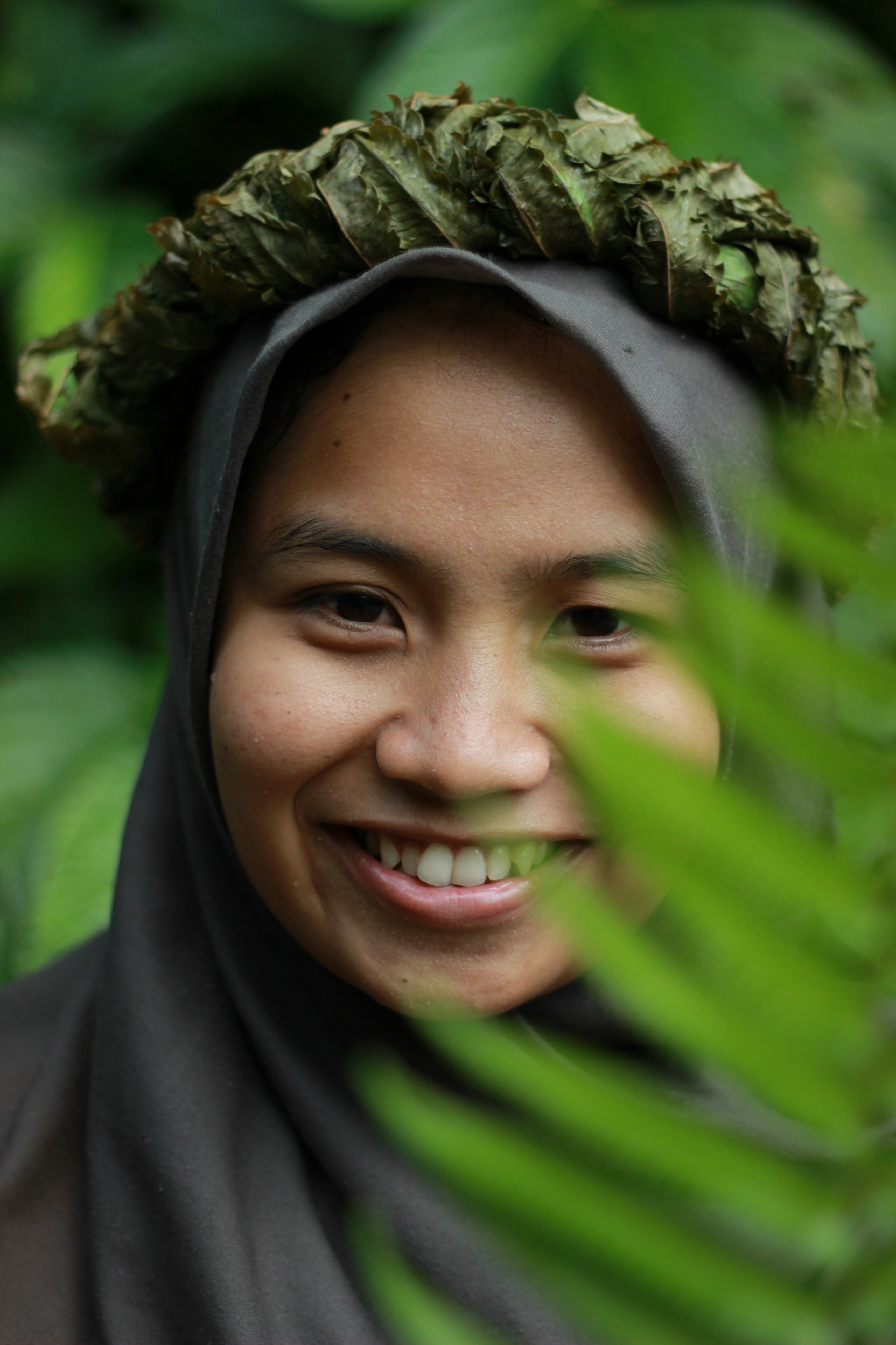 Seorang wanita berselendang tersenyum untuk kamera