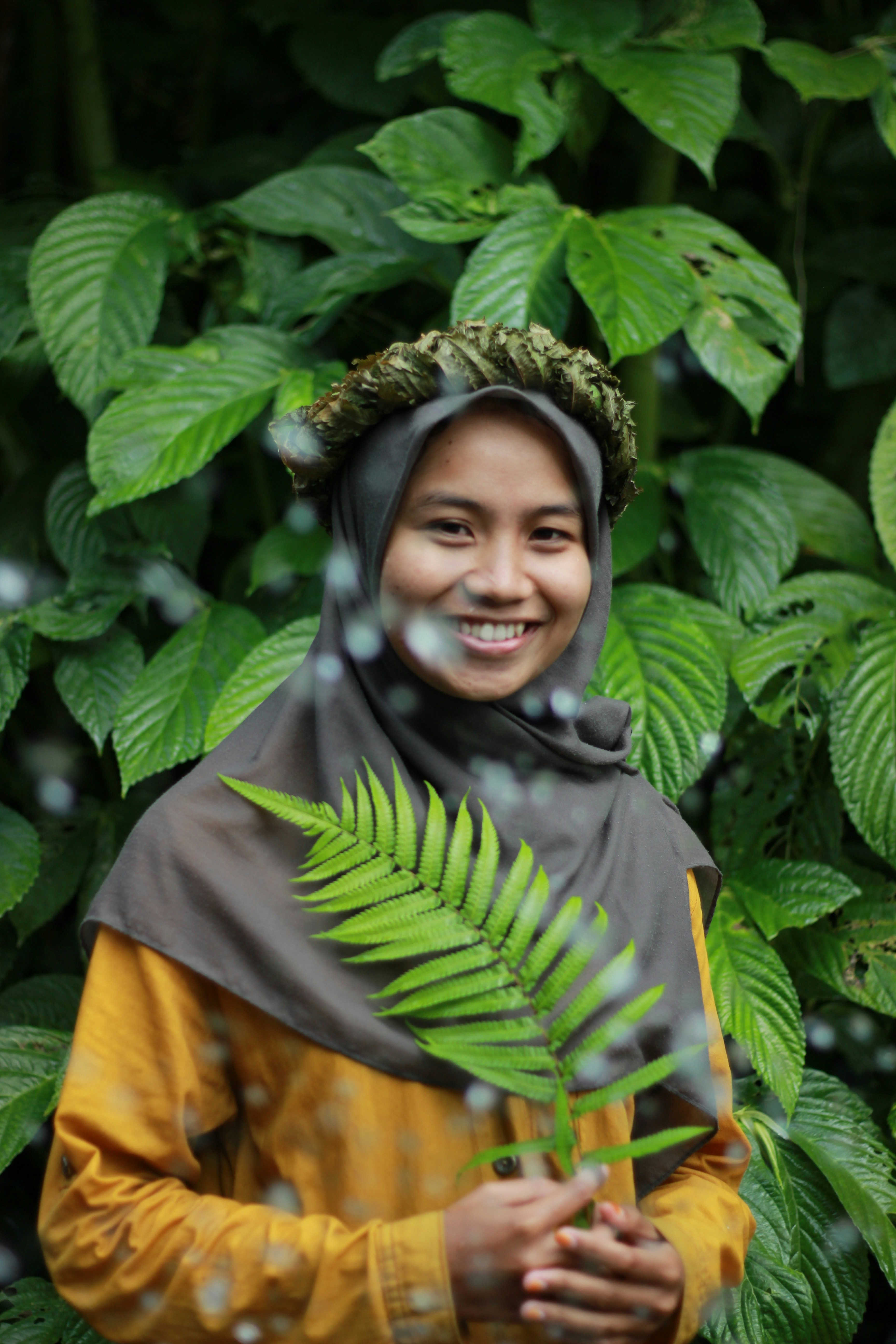 seorang wanita dengan hiasan kepala memegang tanaman hijau