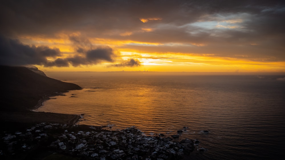 a sunset over a body of water with a mountain in the background