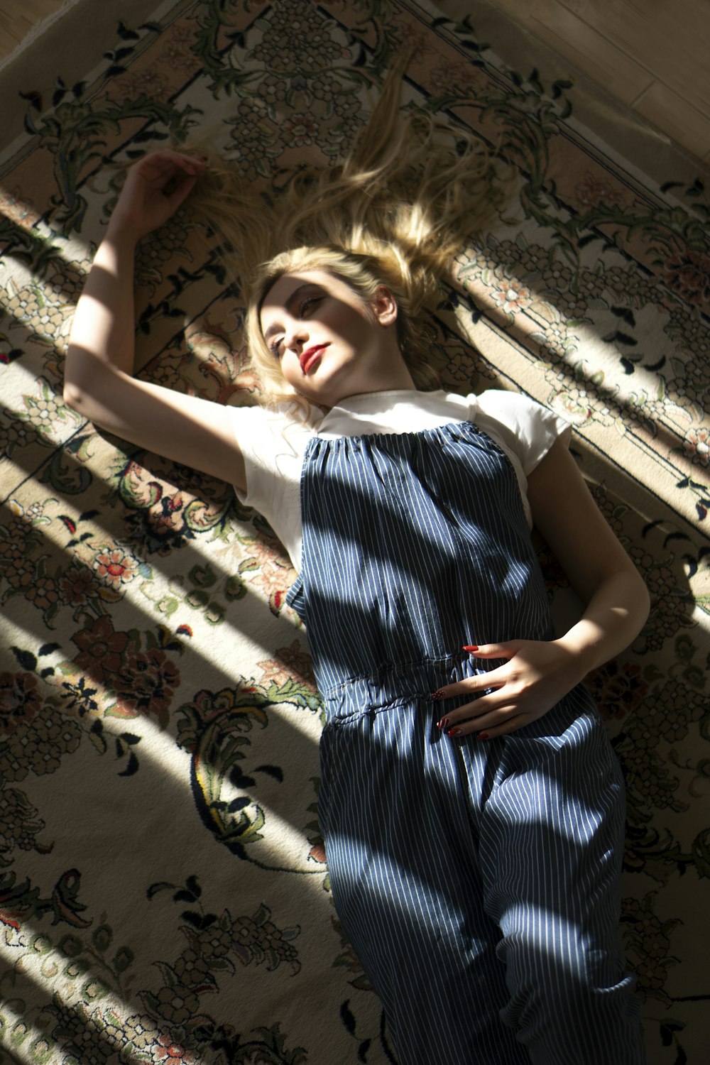 a woman laying on a rug with her hair blowing in the wind