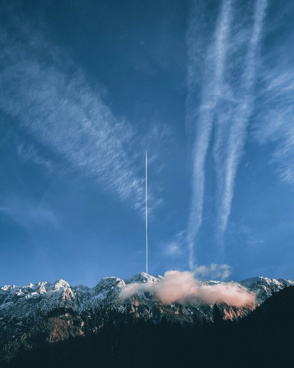 a plane flying in the sky over a mountain range