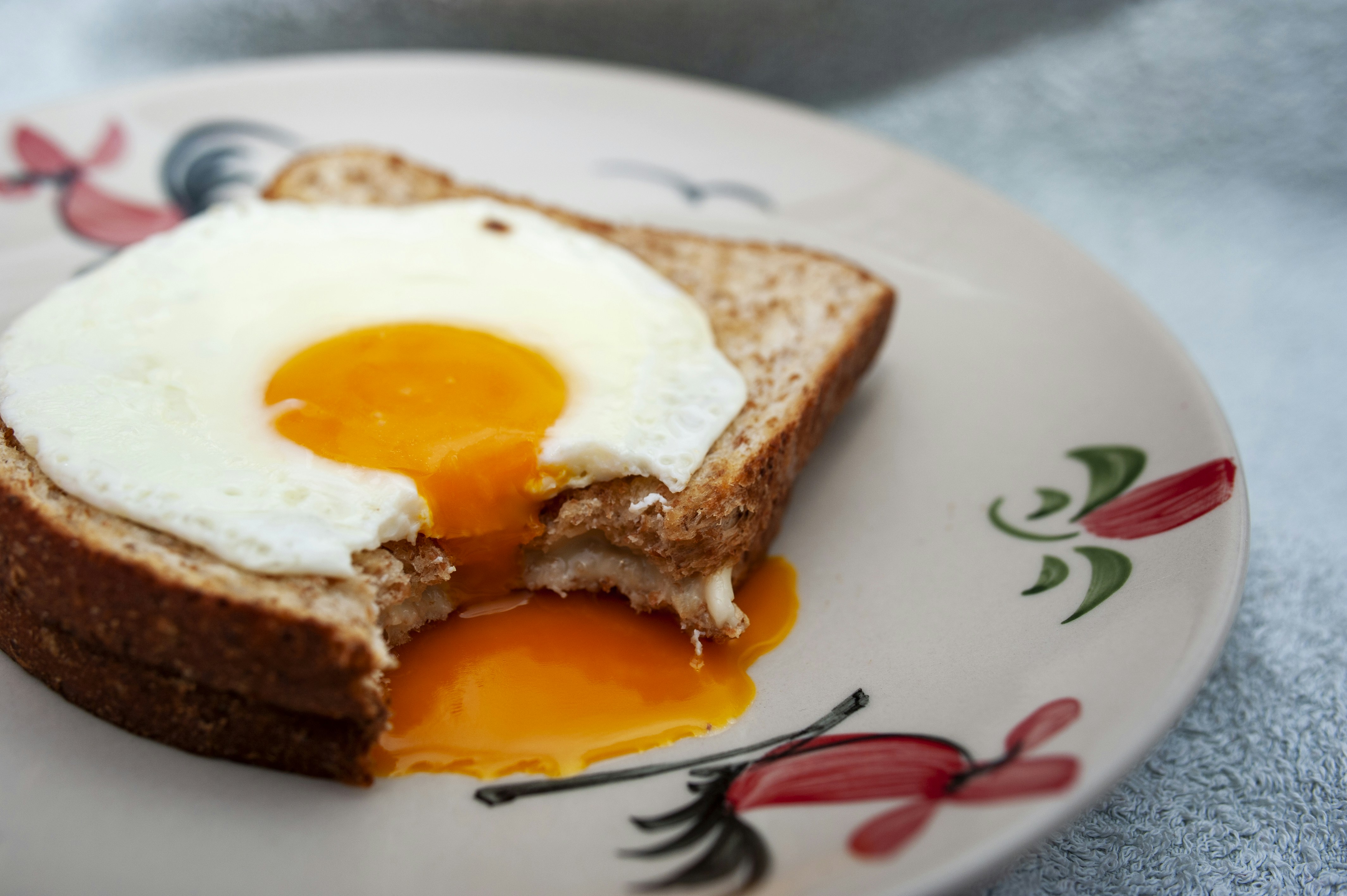 Toast topped with a perfectly runny over easy egg, yolk flowing over the sides - over easy eggs