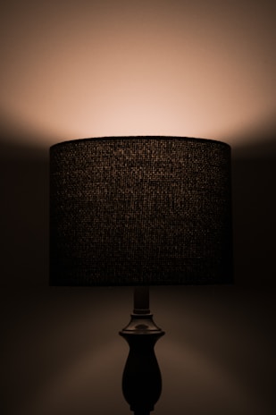 Porcelain lamp base with elegant curves illuminated softly against a dark background.