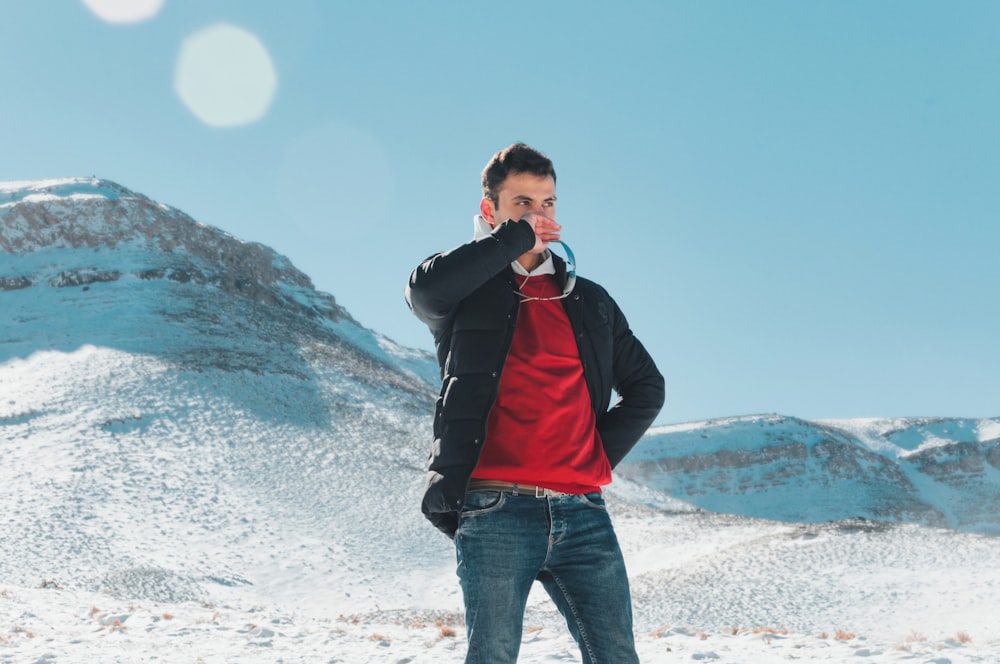 a man in a red shirt and black jacket standing in the snow