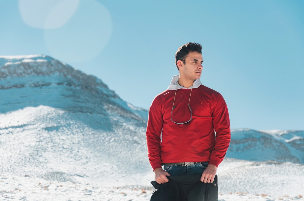 a man standing in the snow with a mountain in the background