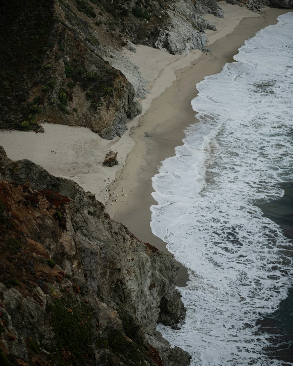 a sandy beach next to a rocky cliff