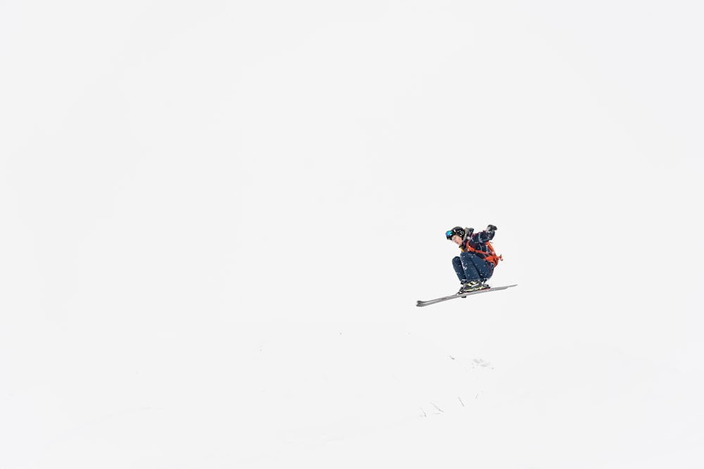 a man riding a snowboard down the side of a snow covered slope