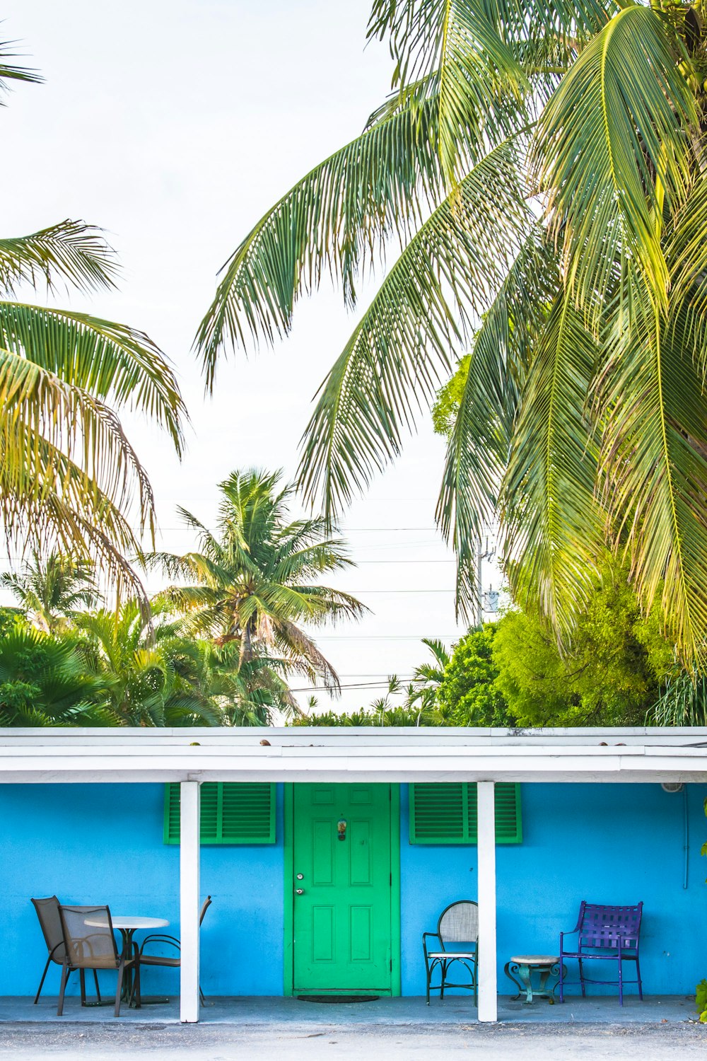 a blue building with two chairs and a green door