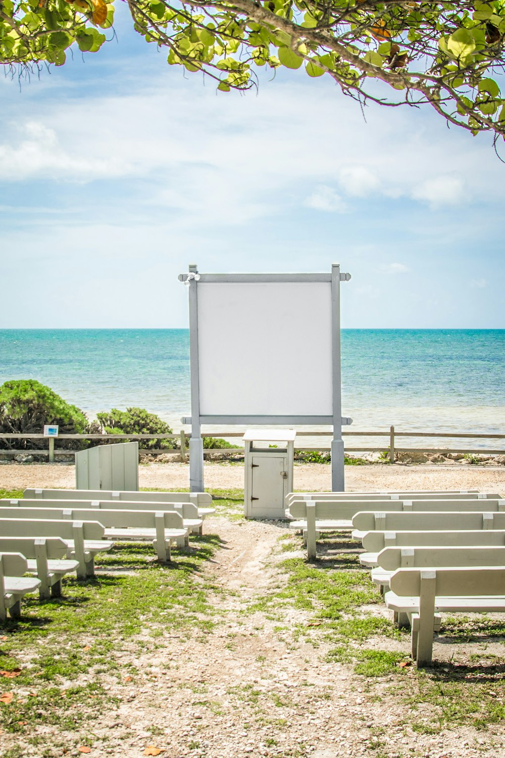 an empty beach with rows of benches and a large screen