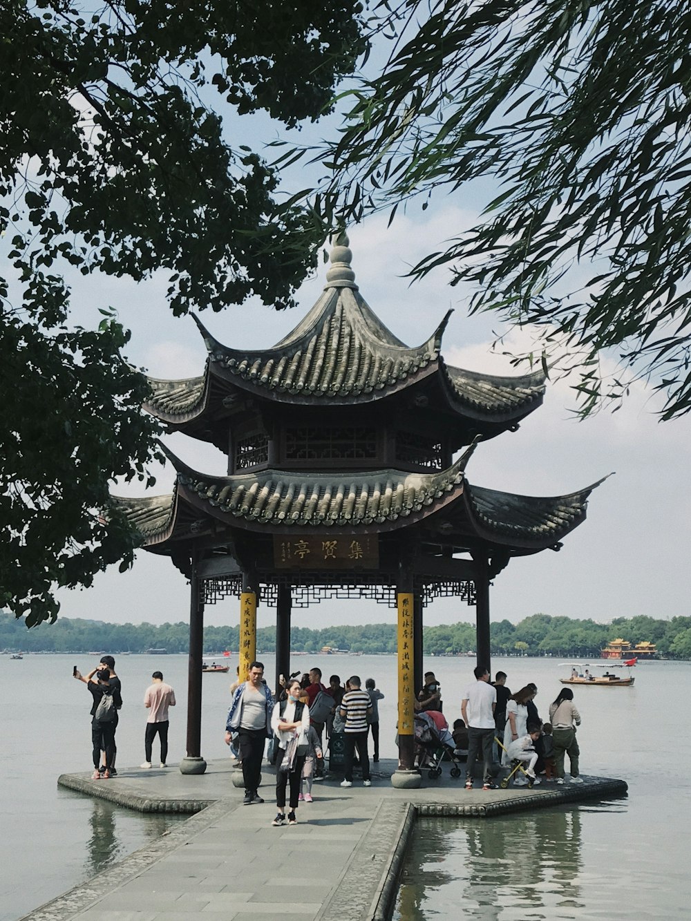 a group of people standing on a pier next to a body of water