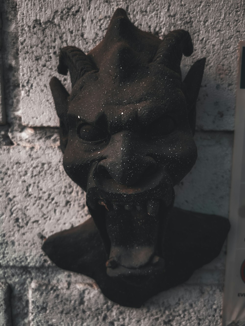 a statue of a demon on a brick wall