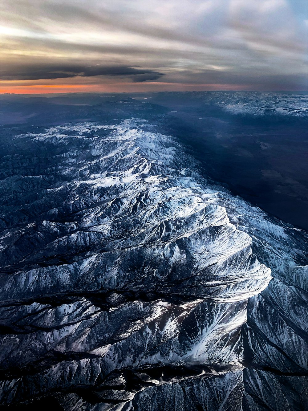 an aerial view of a mountain range at sunset