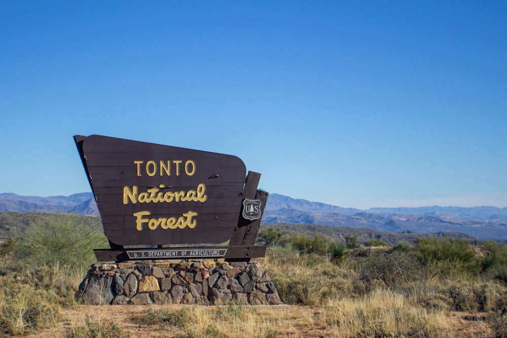 a sign in the middle of a field with mountains in the background