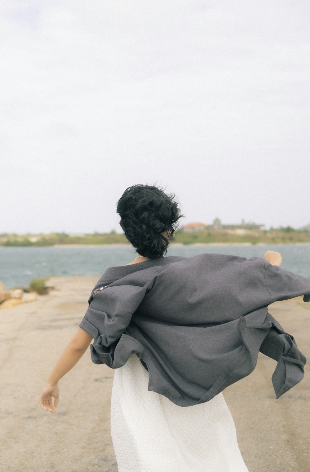 a woman walking down a road next to a body of water