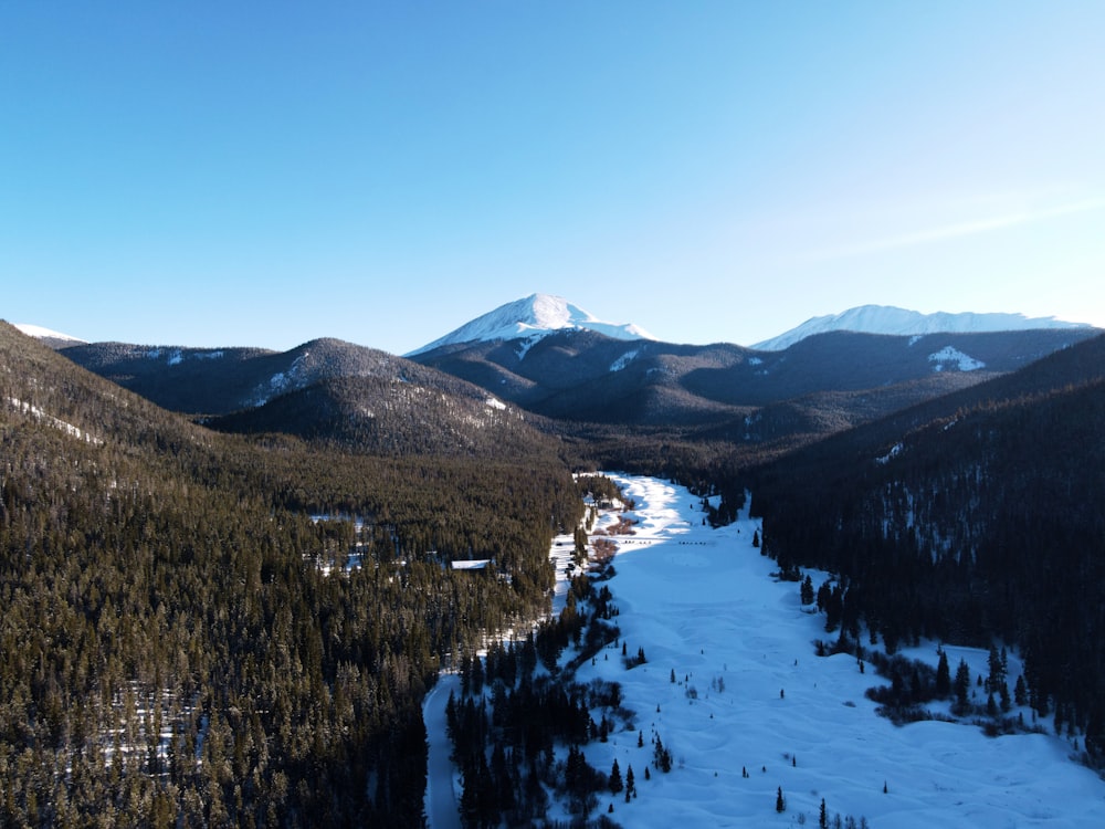 uma vista de uma montanha coberta de neve com um rio que a atravessa
